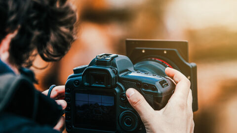 Bild zeigt einen Fotografen mit seiner Kamera.