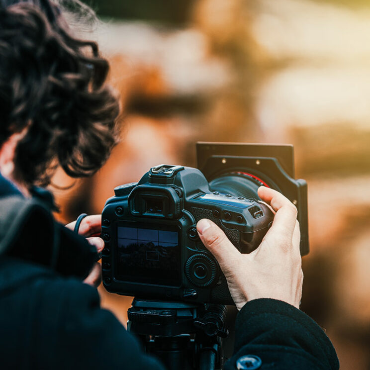 Bild zeigt einen Fotografen mit seiner Kamera.